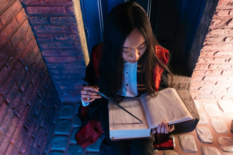 A Woman Holding a Wand while Reading a Book